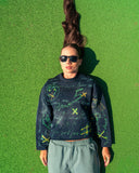 Model lying on a tennis court wearing the North Bioko Club 5X Graffiti Sweatshirt in Navy