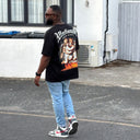 Back view of customer wearing a black North Bioko Club T-shirt with large angel artwork and flame graphic