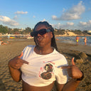 Customer wearing a white North Bioko Club graphic T-shirt with red and black artwork at the beach