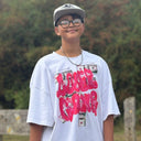 Customer wearing an oversized white North Bioko Club graphic T-shirt with pink artwork outdoors