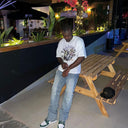 Customer wearing a white North Bioko Club Trapped graphic T-shirt in an evening outdoor setting