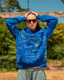 Model wearing the Cobalt Blue Graffiti Hoodie with all-over hand-painted scribbles and yellow X details